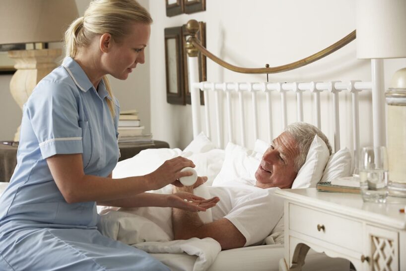 Nurse giving medication to a patient in bed.