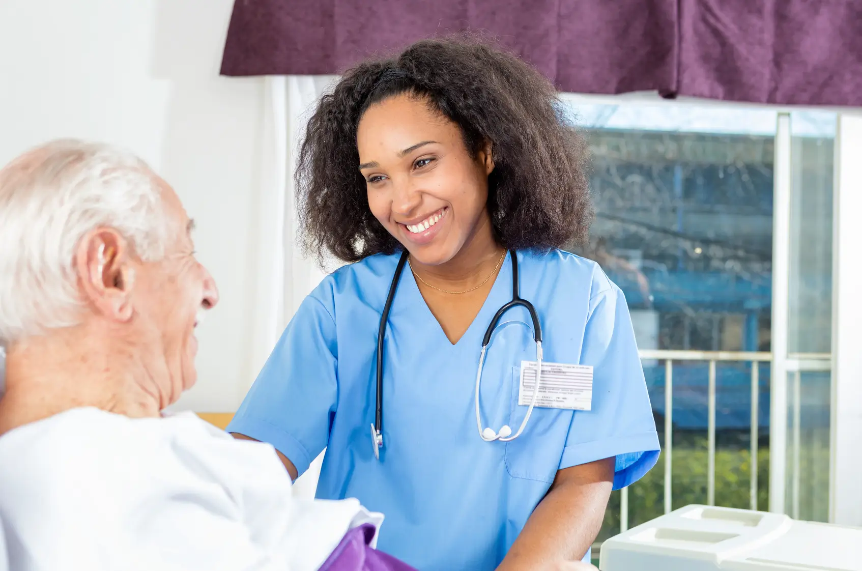 Nurse smiling at elderly patient in hospital.